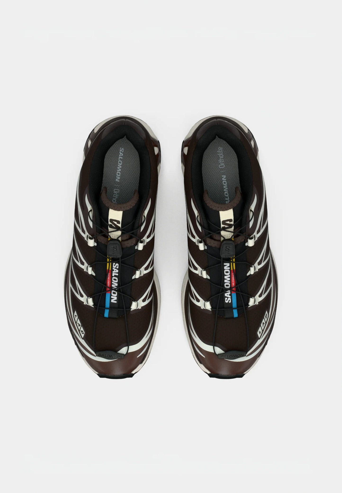 Scarpe sportive marroni con una superficie texturizzata, dettagli bianchi e un sistema di allacciatura rapida. Presentano una soletta imbottita per il massimo comfort.