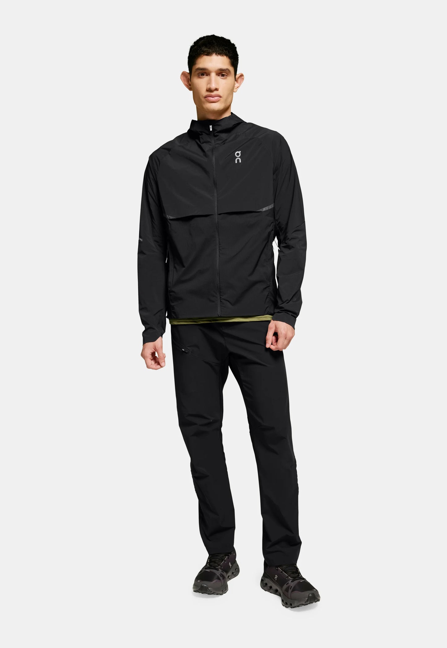 Giacca leggera nera con chiusura a zip e dettagli riflettenti, abbinata a pantaloni neri coordinati e scarpe scure. Texture uniforme in tutto.