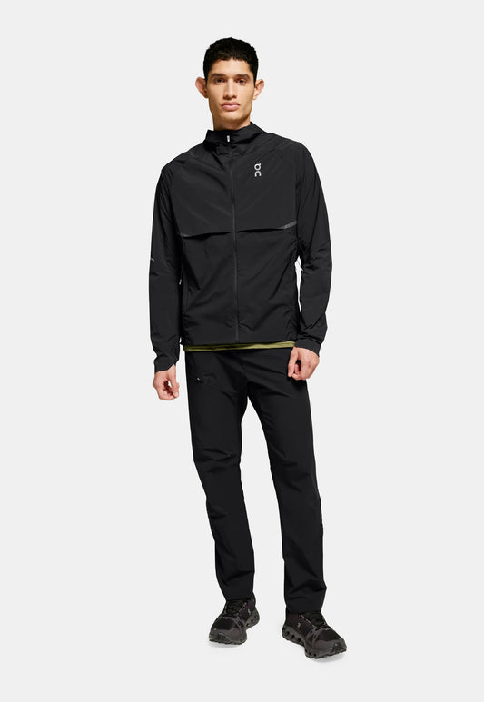 Giacca leggera nera con chiusura a zip e dettagli riflettenti, abbinata a pantaloni neri coordinati e scarpe scure. Texture uniforme in tutto.