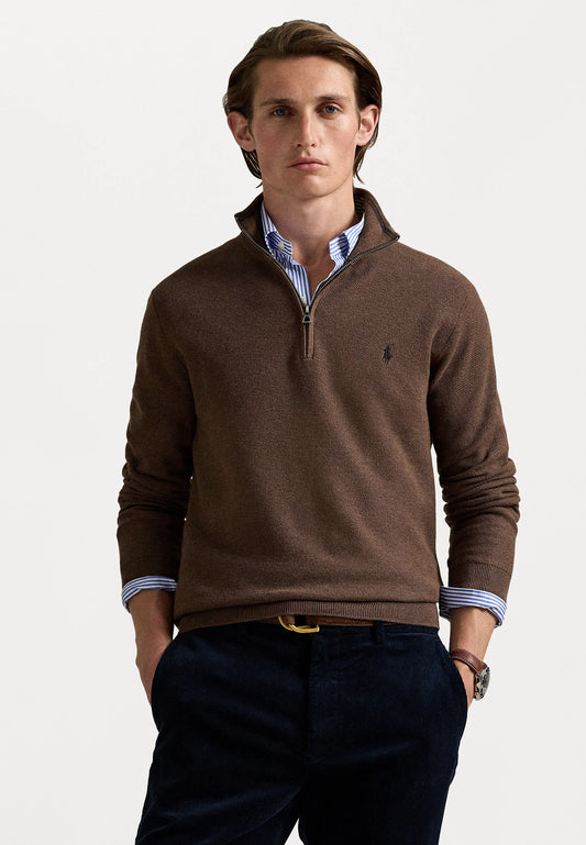 Jersey marrón con cremallera en el cuello sobre una camisa con botones a rayas, combinado con pantalones azul marino y mocasines marrones. Detalles notables incluyen el cinturón y el reloj.