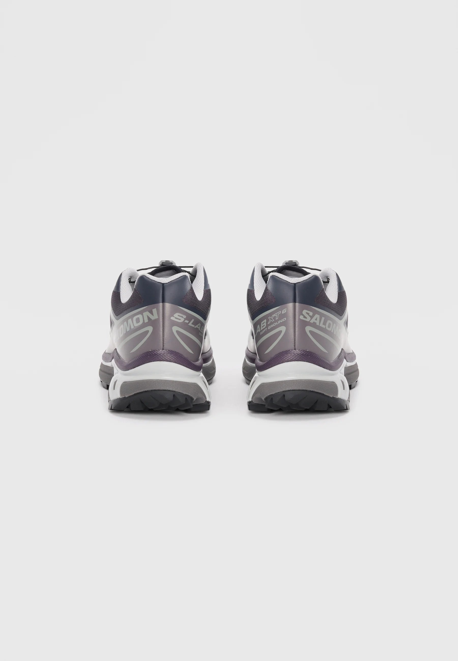 Scarpe da trail running nere e viola con accenti grigi, dotate di una suola testurizzata e di un sistema di laccio sicuro. Branding sulla parte laterale.