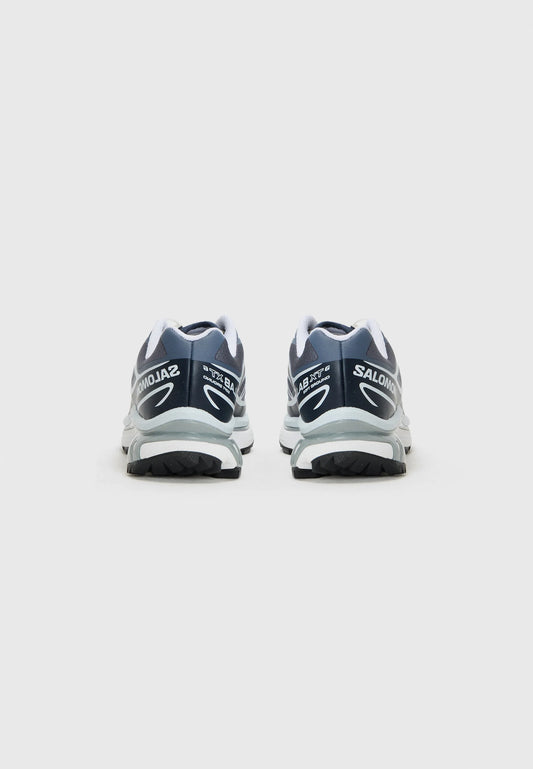 Scarpe da corsa blu scuro con accenti bianchi, dotate di un colletto imbottito e suola testurizzata. Marchio visibile sul tallone e sul lato.