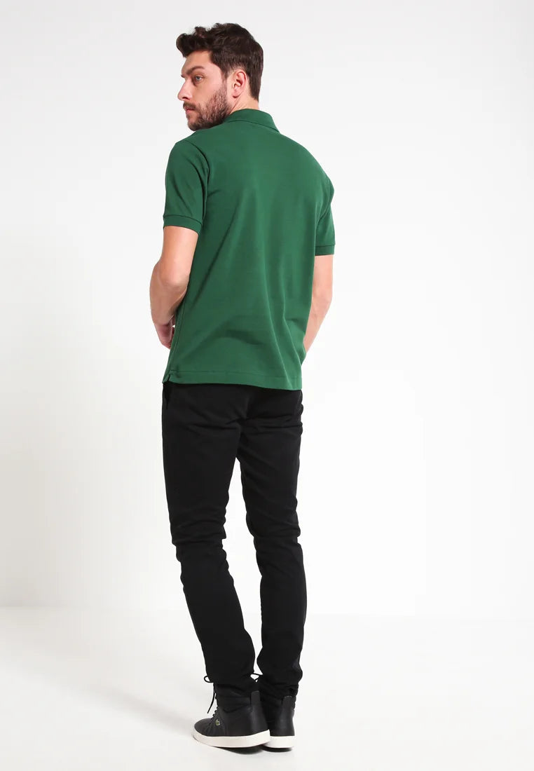 Polo verde con orlo dritto, maniche corte e colletto, abbinato a pantaloni neri e scarpe nere, visto da dietro.