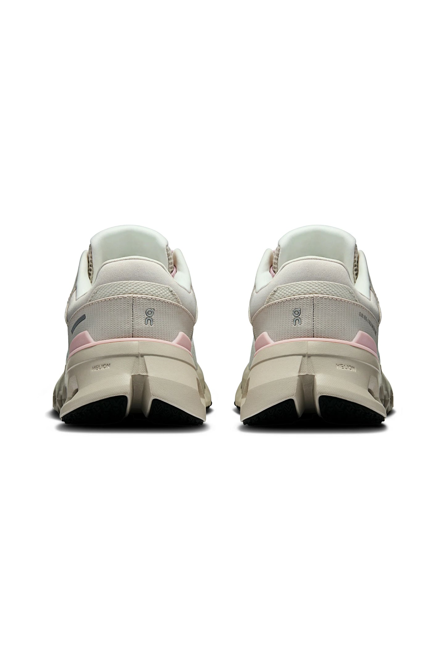 Una coppia di scarpe da ginnastica beige e rosa vista da dietro, con suole spesse e loghi del marchio ben visibili sui talloni.