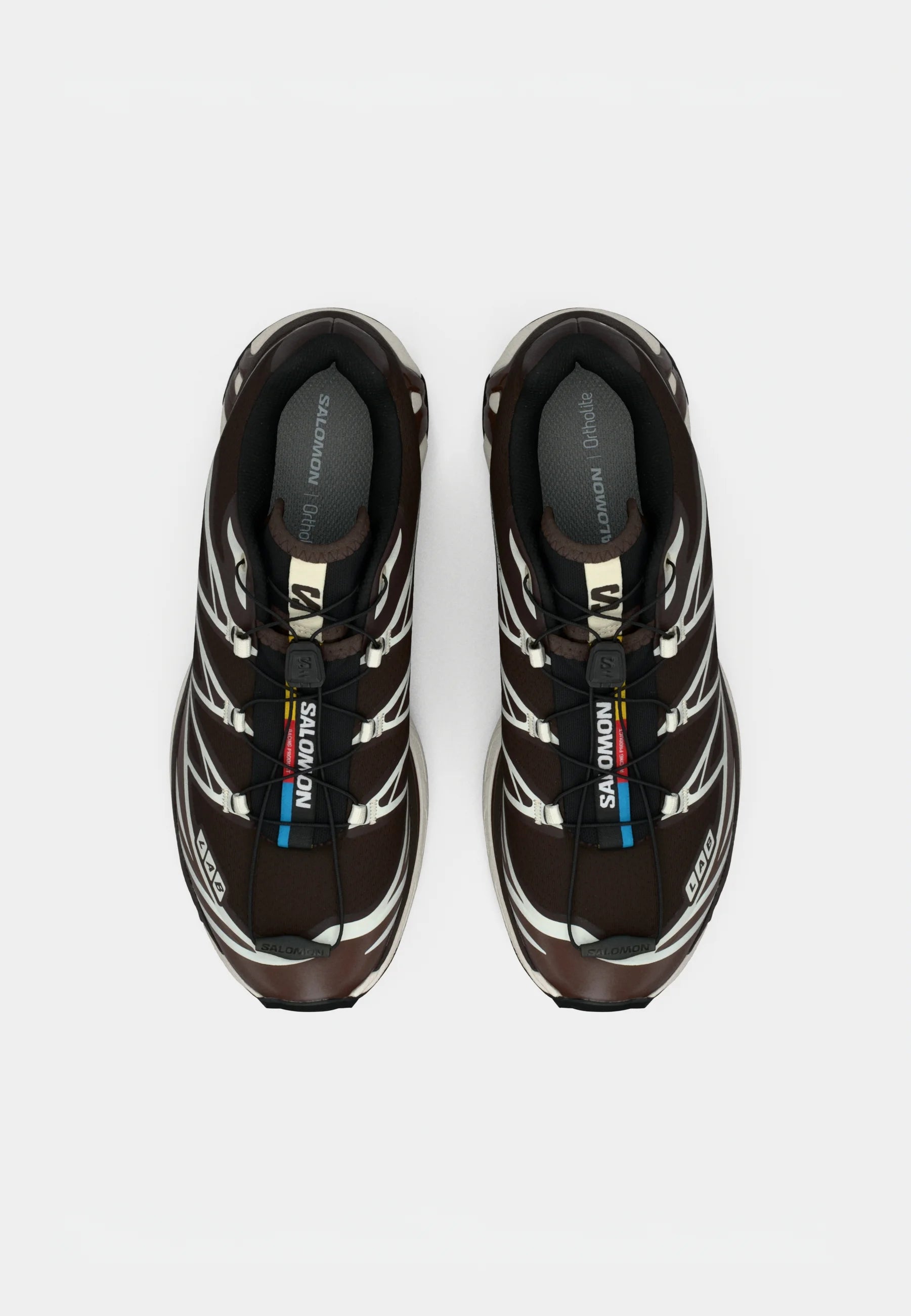 Scarpe sportive marroni con una superficie texturizzata, dettagli bianchi e un sistema di allacciatura rapida. Presentano una soletta imbottita per il massimo comfort.