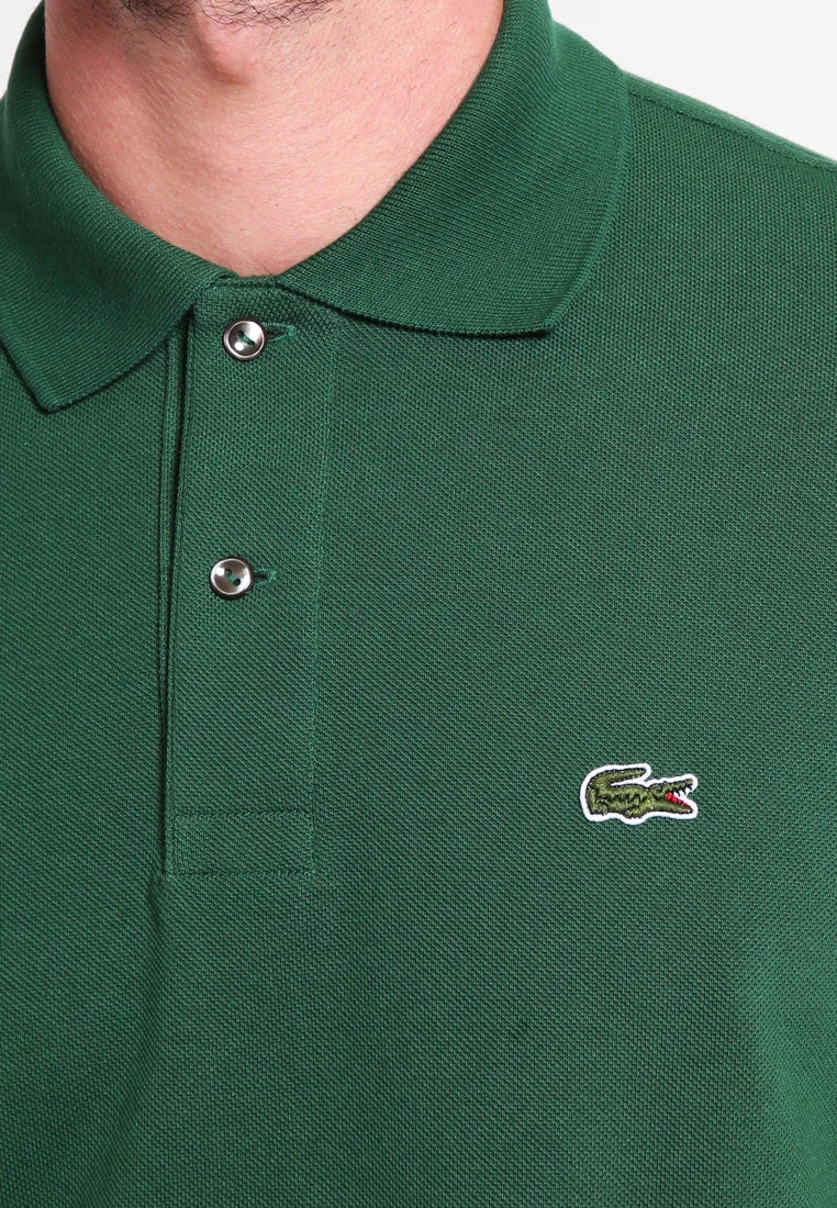 Polo shirt verde con tessuto texture, due bottoni argentati sul colletto e un piccolo logo di coccodrillo ricamato sul lato sinistro.