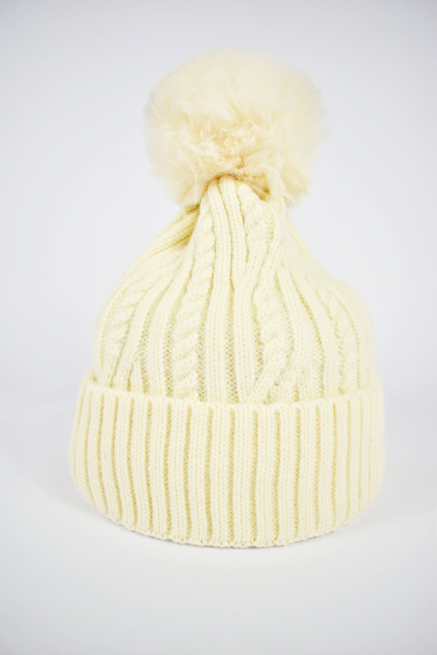 Cappello invernale donna color crema a trecce con risvolto doppio e pompon in pelliccia ecologica.