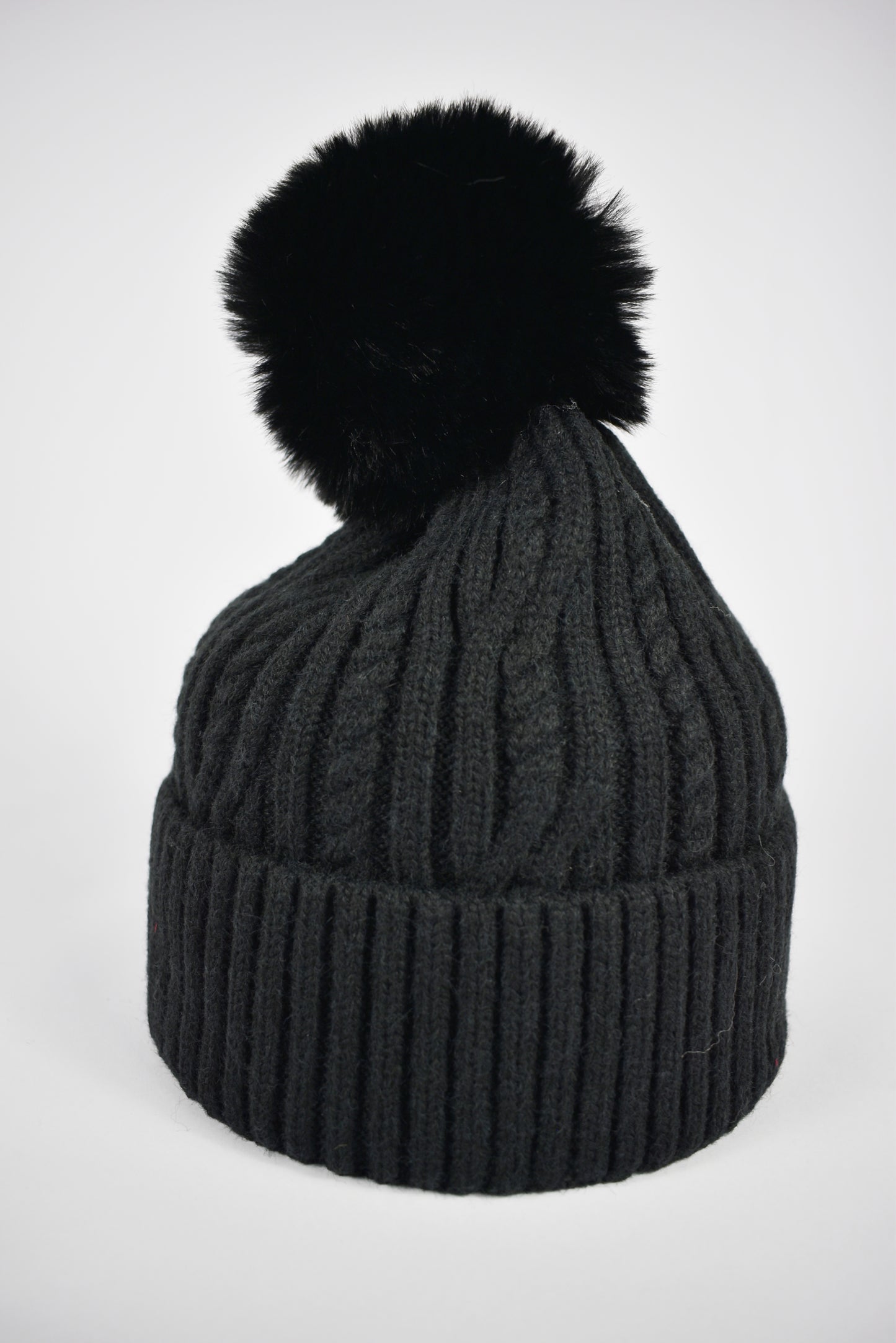 Berretto nero da donna a trecce con risvolto e pompon morbido in pelliccia ecologica, ideale per l'inverno.