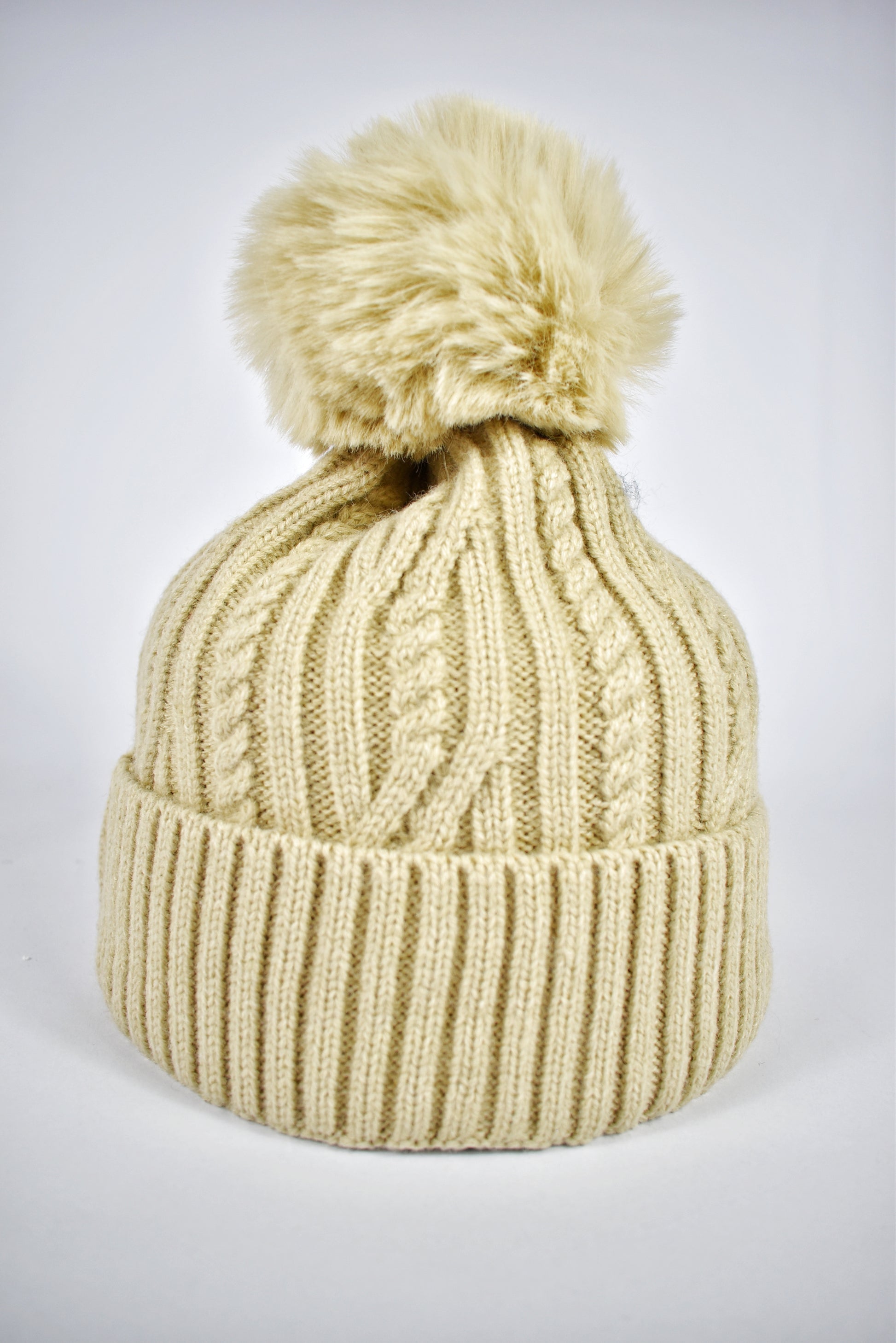 Berretto beige da donna a trecce con risvolto e pompon in pelliccia ecologica, accessorio invernale morbido.